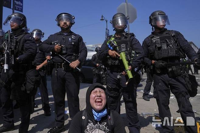 [로스앤젤레스=AP/뉴시스] 8일(현지 시간) 미 캘리포니아주 로스앤젤레스 도심의 메트로폴리탄 구치소 인근에서, 이민세관단속국(ICE)의 불법 이민자 단속 및 체포에 항의하는 시위대가 경찰과 대치한 가운데 한 여성이 비명을 지르고 있다. 도널드 트럼프 대통령은 불법 이민자 단속에 항의하는 시위에 참여하는 사람들은 마스크를 착용해서는 안 된다고 밝혔다. 2025.06.09.