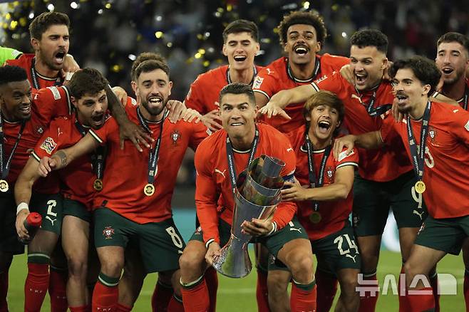 [뮌헨=AP/뉴시스] 포르투갈의 크리스티아누 호날두가 8일(현지 시간) 독일 뮌헨의 알리안츠 아레나에서 열린 2024-25 유럽축구연맹(UEFA) 네이션스리그(UNL) 스페인과의 결승전에서 승리해 우승한 후 트로피를 들고 동료들과 함께 환호하고 있다. 포르투갈은 연장까지 2-2 무승부를 기록해 승부차기 끝에 5-3으로 승리해 6년 만에 정상에 올랐다. 호날두는 후반 16분 동점 골을 넣어 A매치 138호 골을 기록했다. 2025.06.09.