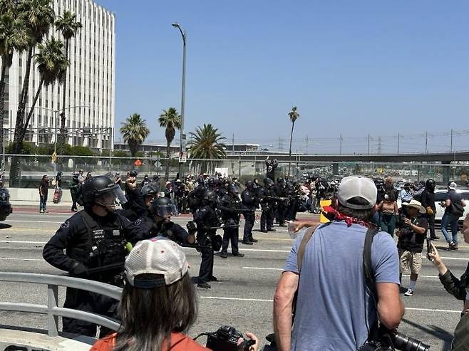 LA에서 시위대와 대치 중인 경찰 (로스앤젤레스=연합뉴스) 임미나 특파원 = 8일(현지시간) 미국 로스앤젤레스(LA) 도심의 연방 구금시설인 '메트로폴리탄 디텐션 센터'(Metropolitan Detention Center, 이하 MDC) 앞 대로에서 경찰과 시위대가 대치하고 있다. 시위대는 미 이민세관단속국(ICE)의 대대적인 불법이민자 단속에 반발하는 시위를 사흘째 벌이고 있다. mina@yna.co.kr