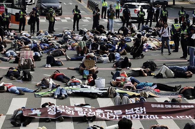정의로운 전환 2025 공동행동 회원들이 대행진 도중 다이인(die-in, 참가자들이 죽은 척하는 시위) 행위극을 하고 있다.
