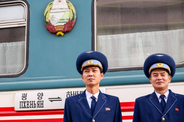 북한 철도 승무원이 지난해 12월 러시아 연해주 하산역에 정차한 열차 앞에서 자세를 잡아보이고 있다. 하산(러시아)=타스 연합뉴스