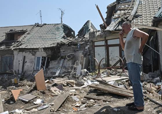 9일(현지시간) 우크라이나 자포리자의 한 주민이 러시아의 공격으로 부서진 건물 잔해를 보고 있다. 로이터=연합뉴스