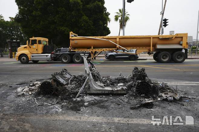[로스앤젤레스=AP/뉴시스] 9일(현지 시간) 미 캘리포니아주 로스앤젤레스(LA) 도로에 이민세관단속국(ICE)의 이민자 단속에 반대하는 시위로 불에 탄 차량 잔해가 놓여 있다. 미 군 당국은 LA 불법 이민자 단속 반대 시위에 약 700명의 해병대원을 투입한다고 공식 발표했다. 2025.06.10.