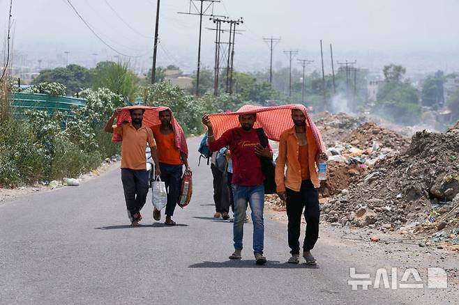 [AP/뉴시스] 10일 인도 잠무에서 사람들이 강한 햇볕을 피하기 위해 스카프를 둘러쓰고 걷고 있다