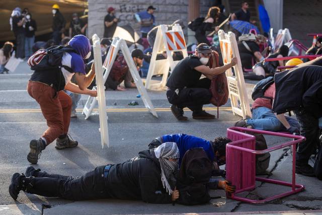 8일(현지 시간) 미국 캘리포니아주 로스앤젤레스 시내에서 벌어진 연방 이민 단속 반대 시위 도중 시위대가 경찰이 발사한 비살상탄을 피해 공원 의자와 표지판 뒤에 몸을 숨기고 있다. 로이터연합뉴스