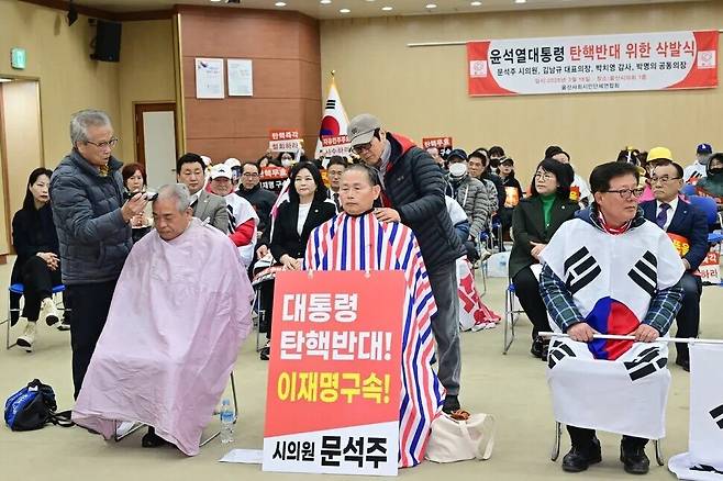 지난 3월18일 울산시의회 대강당에서 국민의힘 문석주 시의원이 윤석열 탄핵을 반대하는 보수단체 회원들과 함께 삭발하고 있다. 이 자리에 참석한 같은당 소속 이성룡·이영해·안대룡·천미경 시의원이 뒷줄에 앉아있다. 울산시의회 제공