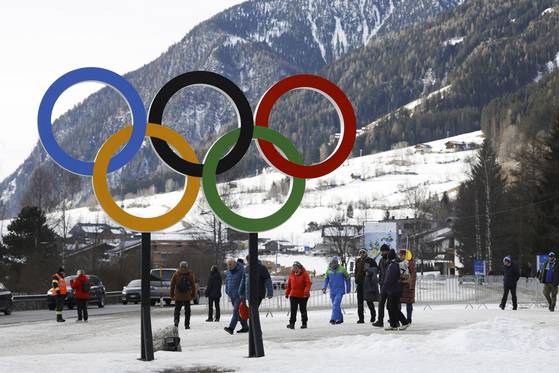 People walk near Olympic rings near the village of Anterselva where the Biathlon will take place during the Milan Cortina 2026 Winter Olympics, in northern Italy, Saturday, Jan. 25, 2025. [AP/YONHAP]