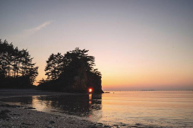 충남 서해안 반도 태안군 구멍바위 사이로 해가 지고 있다. 구멍 사이로 보이는 굴뚝과 건물은 태안발전본부다. 이런 멋진 장면은 6월에 볼 수 있다.