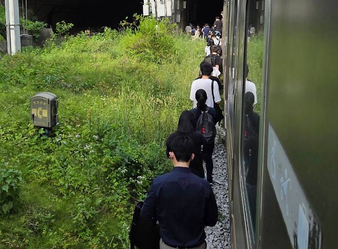 13일 오전 경의중앙선 신촌역 인근에서 서울역행 경의중앙선 열차가 단전으로 인해 신촌역 앞 50m지점에서 멈취 승객들이 열차에서 내려 신촌역으로 걸어가고 있다. /뉴스1