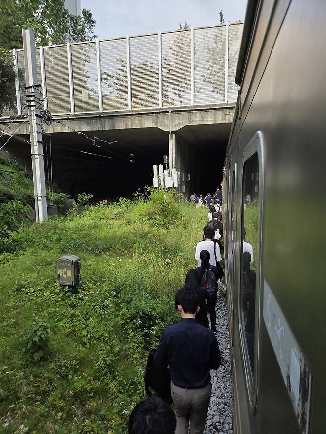 13일 오전 경의중앙선 신촌역 인근에서 사다리차 전도사고가 발생해 서울역∼항공대역 구간이 양방향 통제된 가운데 서울역행 경의중앙선 열차에 탑승한 승객들이 열차에서 내려 선로를 따라 대피하고 있다. (독자 제공 / 뉴스1)