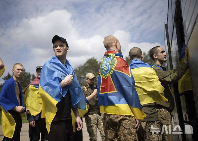 [체르느히우=AP/뉴시스] 9일(현지 시간) 우크라이나 체르느히우에서 러시아와의 포로 교환으로 석방된 우크라이나 군인들이 국기를 몸에 두른 채 버스에 오르고 있다. 러시아와 우크라이나가 25세 미만과 중상자 포로를 교환했다. 2025.06.13.