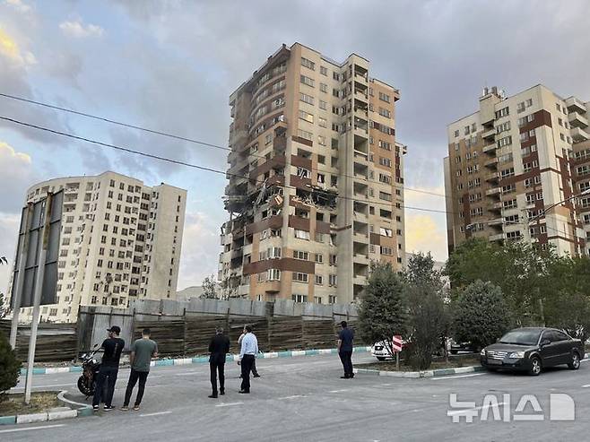 [테헤란=AP/뉴시스] 13일(현지 시간) 이란 테헤란에서 주민들이 이스라엘의 공습으로 파손된 아파트 건물을 지켜보고 있다. 이스라엘방위군(IDF)은 이날 새벽 이스라엘이 이란의 핵·군 시설에 대한 선제타격을 개시했다고 성명을 통해 밝혔다. 2025.06.13.