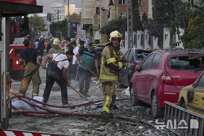 [테헤란=AP/뉴시스] 13일(현지 시간) 이란 테헤란 북부의 한 주거 단지에서 이스라엘의 공습으로 폭발이 발생한 후 소방관들과 주민들이 잔해를 치우고 있다. 이스라엘방위군(IDF)은 이날 새벽 이스라엘이 이란의 핵·군 시설에 대한 선제타격을 개시했다고 성명을 통해 밝혔다. 2025.06.13.