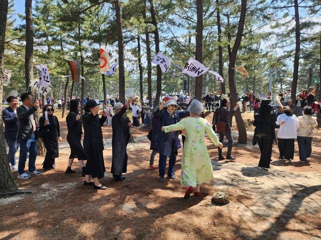 연둣빛 원피스에 빨간 구두를 신은 박정자씨가 만장 행렬을 함께하며 지인들과 흥겹게 춤을 추고 있다. 권오두