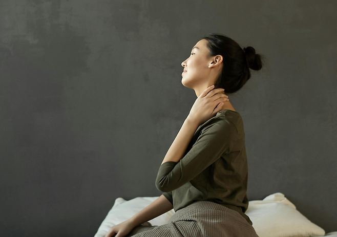 왼손을 뒷목에 얹고 있는 여성