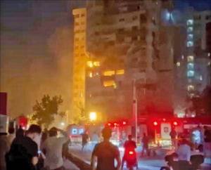 이란 수도 테헤란 시민들이 13일 이스라엘 공습으로 파괴된 건물을 바라보고 있다.  /로이터연합뉴스