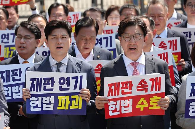 국민의힘 김용태 비상대책위원장과 권성동 원내대표가 지난 11일 이재명 대통령의 공직선거법 위반 사건의 파기환송심을 사실상 무기한 연기한 서울고등법원 앞에서 열린 현장 의원총회에서 구호를 외치고 있다. 연합뉴스.
