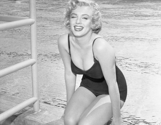 마릴린 먼로가 수영장에서 수영복을 입은 채 특유의 천진난만한 미소를 짓고 있는 모습. [게티이미지닷컴]