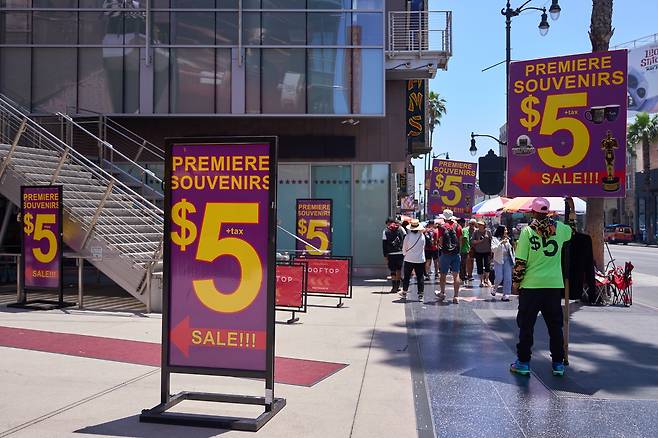 지난달 30일(현지시간) 미국 캘리포니아주 로스앤젤레스(LA) 할리우드 지역에서 사람들이 5달러짜리 기념품 표지판 옆을 지나가고 있다. [EPA]