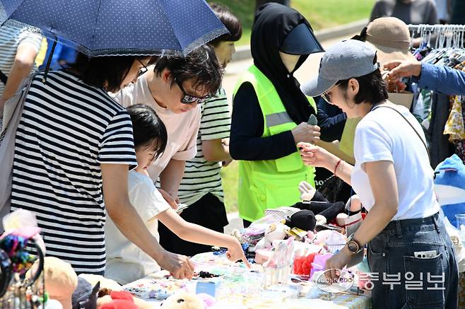 14일 인천시 연수구 송도 센트럴파크에서 열린 송도굿마켓 행사에서 한어린이가 아빠와 함께 물건을 고르고 있다.정선식기자
