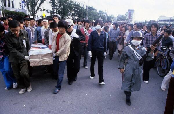 &nbsp;시신 운구 모습. 뒤쪽 하얀 옷 차림에 흰 머리띠를 두르고 있는 사람이 경창수씨. (강연자료를 재촬영한 사진으로, 원본은 프랑수아 로숑 사진)