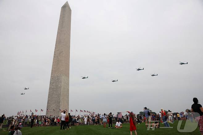 구경꾼들이 14일(현지시간) 워싱턴DC에서 열린 육군 창설 250주년 기념 퍼레이드를 기념하는 헬기 비행을 바라보고 있다. 2025/.06.14.ⓒ 로이터=뉴스1