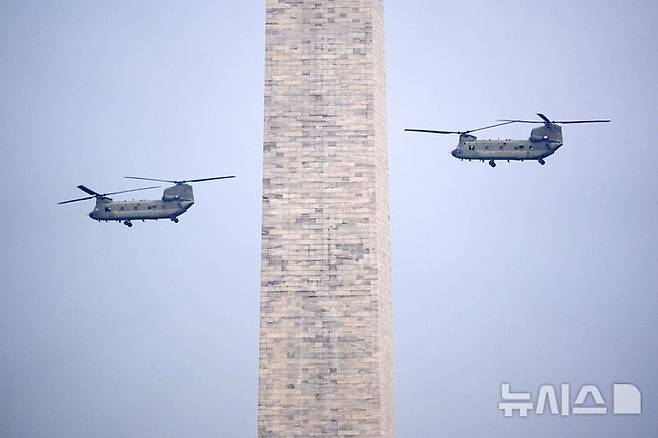 [워싱턴=AP/뉴시스]14일(현지 시간) 미국 워싱턴DC에서 열린 미 육군 250주년 군사 퍼레이드에서 헬기가 워싱턴기념탑 옆을 날아가고 있다. 2025.06.15.