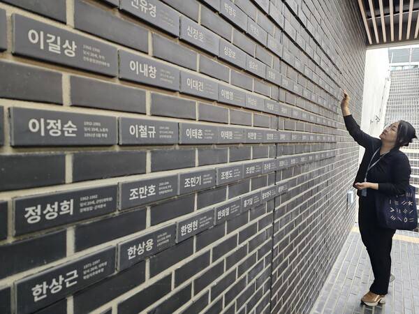 민주화운동기념관 전시 해설사가 지난 13일 오후 벽에 적힌 이름들을 소개하고 있다. 이 벽에는 2001년 민주화운동 관련자 명예회복 및 보상 등에 관한 법률에 따라 민주화운동 관련 사망자로 인정된 136명 이름이 새겨져 있다. /최석환 기자