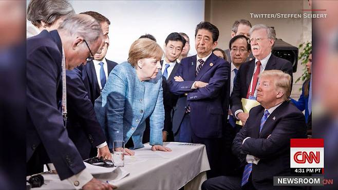 2018년 6월 캐나다에서 열린 주요7개국(G7) 정상회의 당시 앙겔라 메르켈 전 독일 총리가 탁자를 짚고 팔짱을 끼고 있는 도널드 트럼프 미국 대통령과 마주보고 있다. (사진=CNN방송 캡처)