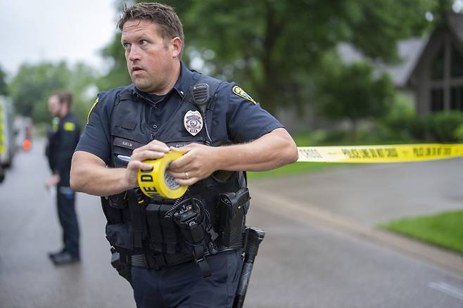 브루클린 파크 경찰서의 한 경관이 14일 미네소타주 브루클린 파크에서 발생한 총격 사건 현장 인근에 경찰 경계선을 설치하고 있다. 2025.06.16 미네소타주=AP 뉴시스