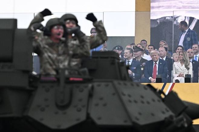 도널드 트럼프 미국 대통령의 79번째 생일이자 미 육군 창설 250주년 기념 열병식이 열린 14일(현지시각) 워싱턴디시(D.C.) 열병식 행사장에서 탱크과 군용 차량들이 행진하는 모습을 트럼프 대통령 등이 지켜보고 있다. 워싱턴/AFP 연합뉴스