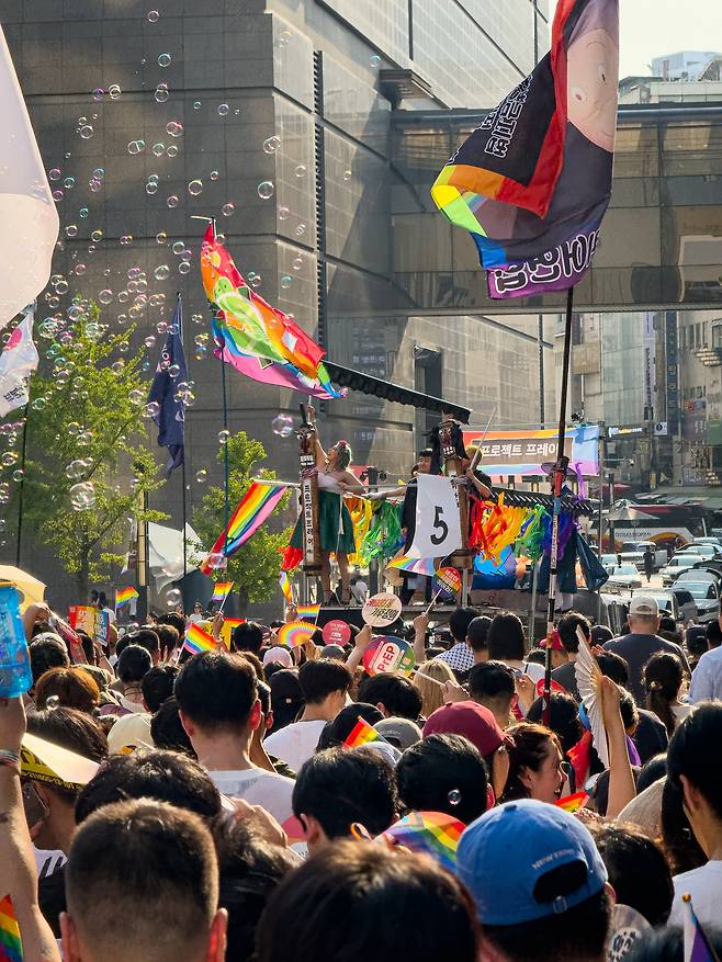 Participants in the Seoul Queer Culture Festival parade watch as a drag queen performs on one of the processional trucks as it passes the Shinsegae Department Store in Jung District, central Seoul, on June 14. [MICHAEL LEE]