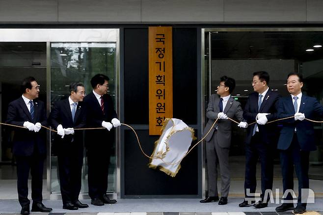 [서울=뉴시스] 김진아 기자 = 이한주(왼쪽 세번째) 국정기획위원회 위원장이 16일 서울 종로구 정부서울청사 창성동 별관에서 열린 국정기획위원회 출범 현판 제막식에서 참석자들과 제막을 하고 있다. 왼쪽 두번째부터 국정기획위원회 김용범 부위원장, 이 위원장, 진성준 부위원장, 방기선 부위원장. (공동취재) 2025.06.16. photo@newsis.com