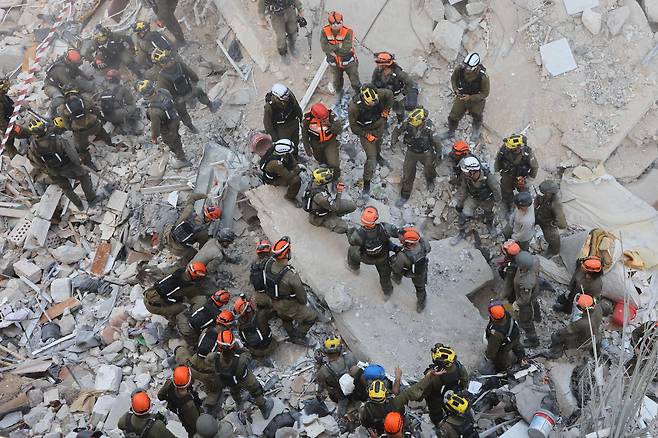 15일 이스라엘 도시 바트얌 한 건물이 이란의 탄도미사일 공격으로 붕괴한 가운데 구조대원들이 생존자를 수색하고 있다/로이터 연합뉴스