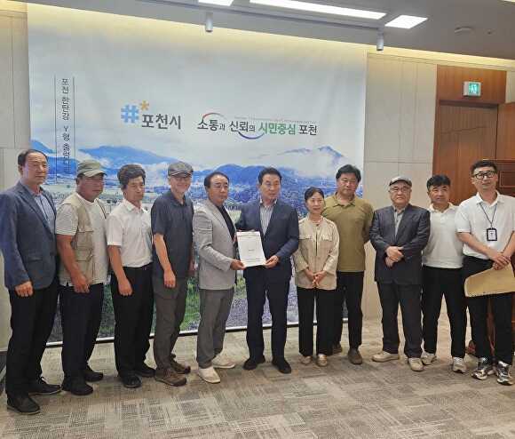 내촌면 주민대표단이 백영현 시장에게 베이스타운 재개장 요구 탄원서를 제출하고 기념 촬영을 하고 있다. [사진=포천시]