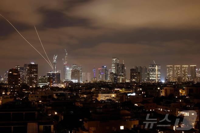 2025년 6월 15일, 이란의 로켓이 이스라엘 텔아비브 상공에서 발사된 가운데 이스라엘 방공 시스템이 가동되어 이란의 미사일을 요격하고 있다.ⓒ AFP=뉴스1