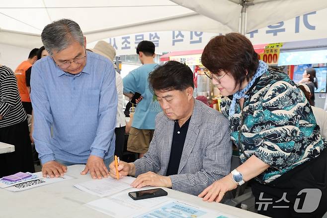 하은호 경기 군포시장(가운데)가 최근 '2025 군포 환경한마당'과 연계해 실시된 '기후위기 시민인식 설문조사'에 참여하고 있다. (군포시 제공. 재판매 및 DB 금지) 2025.6.18/뉴스1