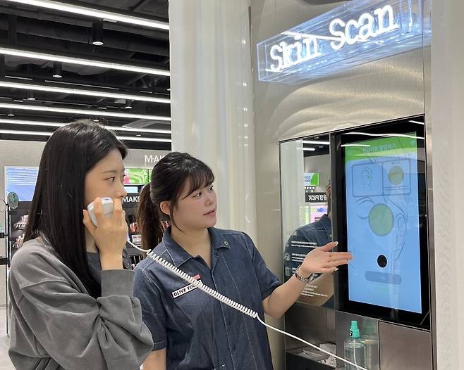 올리브영 합정메세나폴리스점에 도입된 '스킨스캔' 기기에서 피부 측정을 하고 있는 모습/사진=올리브영