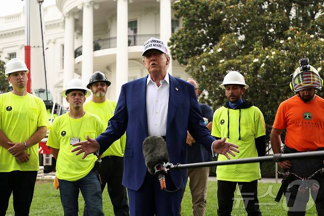 도널드 트럼프 미국 대통령이 18일(현지시간) 워싱턴DC 백악관 남쪽 잔디밭에 새 국기 게양대를 설치하는 작업자들이 지켜보는 가운데, 이란에 대한 직접 공격 여부 등에 대해 답하고 있다. 2025.06.18 ⓒ 로이터=뉴스1 ⓒ News1 류정민 특파원