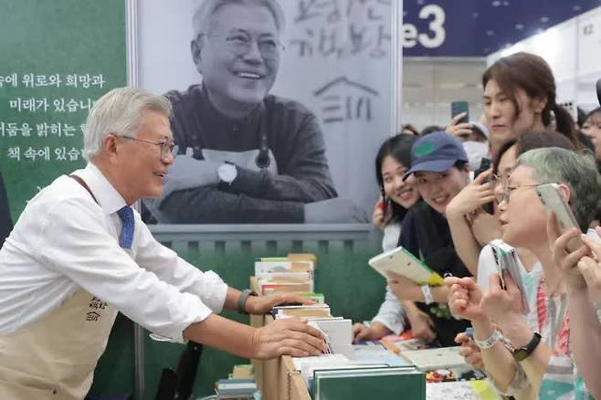 Former President Moon Jae-in (left) greets visitors at the Pyeongsan Bookstore booth during this year’s Seoul International Book Fair at COEX in Gangnam-gu, Seoul, on June 18. / Yonhap News