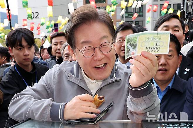 [태백=뉴시스] 조성우 기자 = 이재명 대통령이 대선 후보 당시 강원 태백시 장성중앙시장을 찾아 태백사랑상품권을 꺼내 보이고 있다. 2025.05.03. xconfind@newsis.com