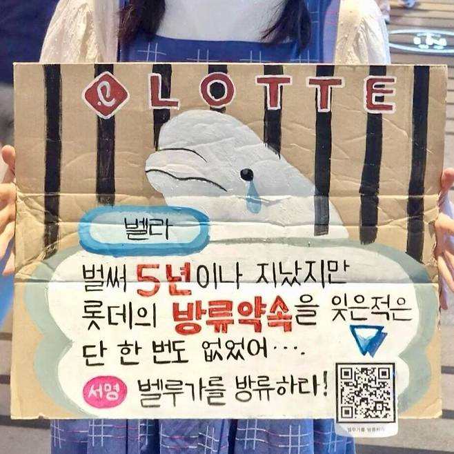 2024년 8월20일 한 시민이 서울 잠실 롯데월드 아쿠아리움 앞에서 손피켓을 들고 서 있다. 핫핑크돌핀스 누리집 갈무리