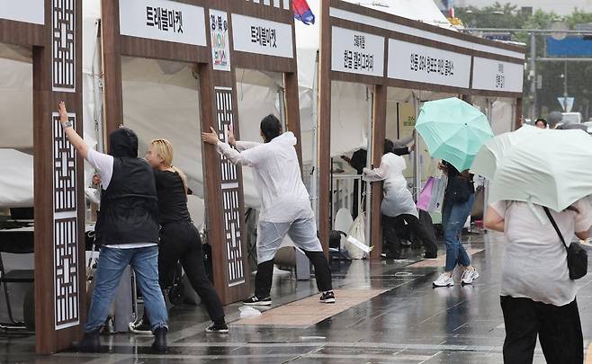 서울에 호우주의보가 내려진 20일 서울 청계광장에서 열린 한 행사장에서 관계자들이 강한 비바람이 불자 시설물을 잡고 있다. 연합뉴스