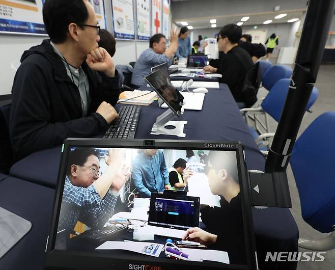 [인천=뉴시스] 전진환 기자 = 정보통신보조기기 체험전시회가 열린 13일 오전 인천 미추홀구 인천시시각장애인복지관 대강당에서 독서확대기 화면에 제품 설명을 듣는 관람객의 모습이 비추고 있다. 2024.05.13. amin2@newsis.com