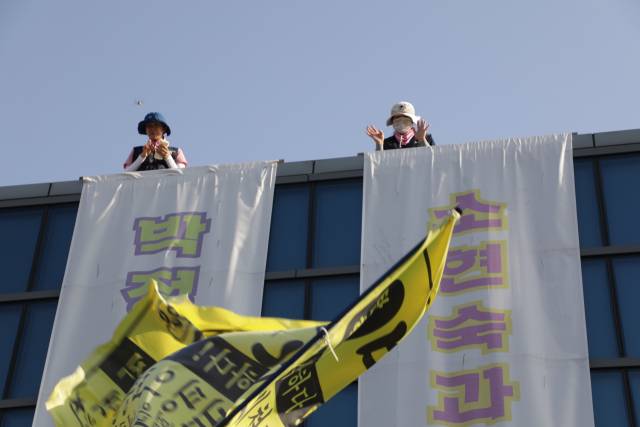 ▲ 한국옵티칼하이테크 정리해고자 박정혜(왼쪽)씨와 소현숙(오른쪽) 씨가 4월 26일 경북 구미공장에서 열린 희망버스 문화제 참가자들에게 손을 흔들고 있다. ⓒ전국금속노조