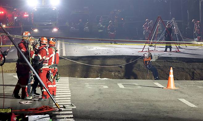 지난 3월 24일 싱크홀(땅 꺼짐) 사고가 발생한 서울 강동구 대명초등학교 인근 사거리에서 소방대원이 내부 구조 작업에 나서고 있다. 연합뉴스