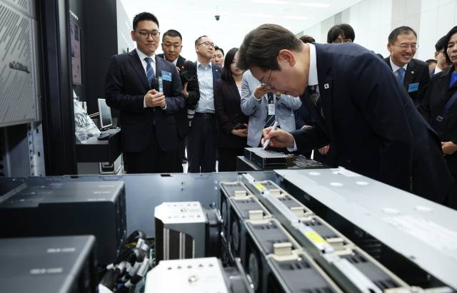 이재명 대통령이 20일 울산전시컨벤션센터에서 열린 인공지능(AI) 글로벌 협력 기업 간담회 뒤 AI 제품·서비스 시연을 참관한 후 제품에 기념 메시지를 남기고 있다. 연합뉴스