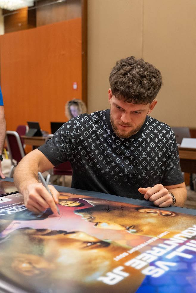 박준용과 경기를 앞두고 UFC 대회 포스터에 사인을 하는 이스마일 나우르디예프. 사진=UFC