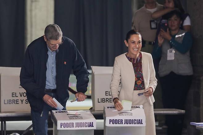 클라우디아 셰인바움 멕시코 대통령(오른쪽)과 그의 남편이 1일 멕시코시티에서 판사 선거장을 찾아 기표를 한 투표용지를 투표함에 넣고 있다. 총 881명의 판사를 모두 선거로 뽑는 멕시코의 판사 직선제 결과 아메리카 대륙에서 ‘마약왕’으로 유명한 호아킨 구스만을 두둔했던 변호사가 판사로 뽑히는 등 갖가지 논란이 불거졌다. 신화 뉴시스