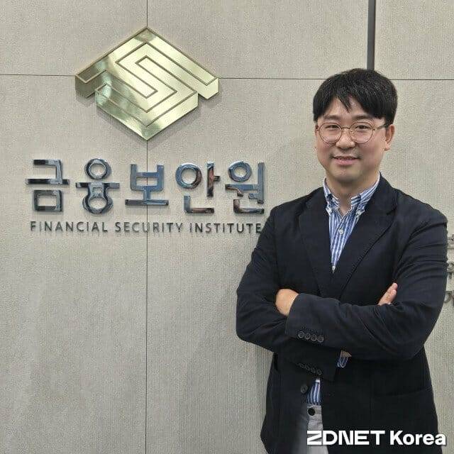 김현민 금융보안원 디지털자산 팀장.  유명 해커이기도한 김 팀장이 서울 여의도 사무소에서 회사 CI를 배경으로 포즈를 취했다.